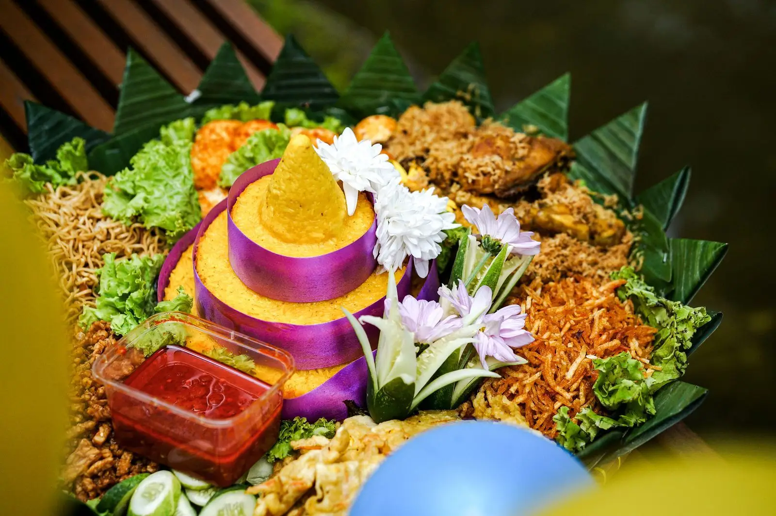 Nasi tumpeng kuning dengan lauk dan hiasan daun pisang (foto ilustrasi).